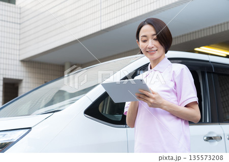車で訪問介護をするミドルの女性介護士 135573208