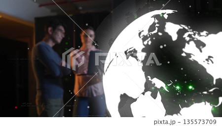 IT pros tapping tablet reviewing data inside datacenter, with LED racks, globe overlay, copy space 135573709