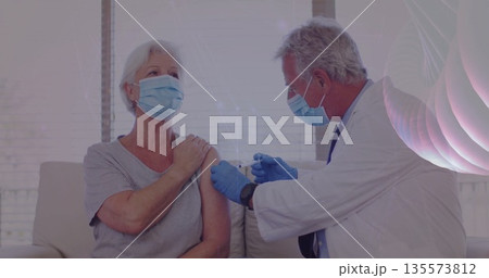 Injecting doctor delivering vaccine to senior female patient in medical office, with syringe 135573812