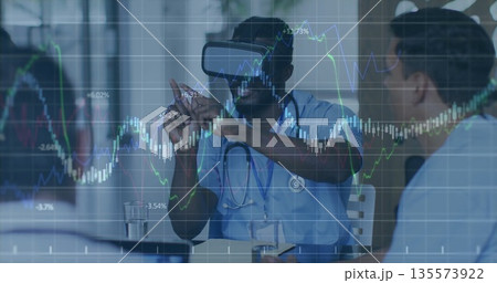 Gesturing physician in scrubs with VR headset demonstrating holographic charts in training room Gesturing physician in scrubs with VR headset demonstrating holographic charts in training room 135573922