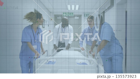 Walking medical team wearing scrubs and lab coat pushing gurney in hospital corridor with exit sign Walking medical team wearing scrubs and lab coat pushing gurney in hospital corridor with exit sign 135573923