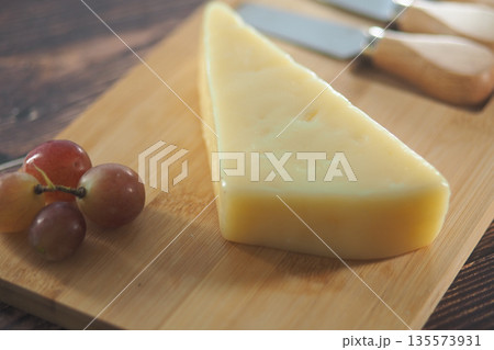 Cheese and grapes on a wooden cutting board 135573931
