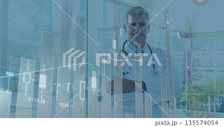 Standing doctor monitoring digital charts in clinic with windows wearing lab coat and stethoscope Standing doctor monitoring digital charts in clinic with windows wearing lab coat and stethoscope 135574054