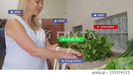 Woman in sleeveless top carrying tote bag selecting greens at stall, floating notification icons 135574115