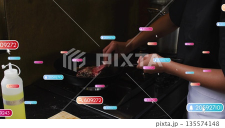 Cook in white apron flipping steak on gas stove, with spatula, data labels, copy space Cook in white apron flipping steak on gas stove, with spatula, data labels, copy space 135574148