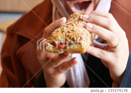 Enjoying a fresh sandwich in a cozy cafe setting during lunchtime Enjoying a fresh sandwich in a cozy cafe setting during lunchtime 135574176