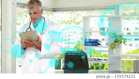 Reviewing doctor wearing lab coat, stethoscope using tablet at medical office with holographic data 135574221