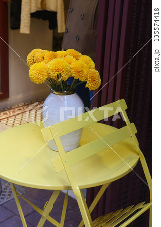 Bright yellow flowers in a vase on a small table in a cozy cafe Bright yellow flowers in a vase on a small table in a cozy cafe 135574418