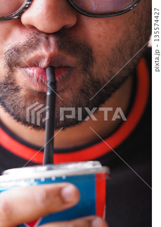 Enjoying a cool drink on a warm day while relaxing outdoors Enjoying a cool drink on a warm day while relaxing outdoors 135574427