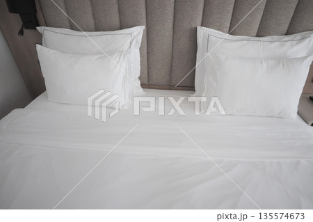 Bed with white sheets and pillows in a simple room Bed with white sheets and pillows in a simple room 135574673