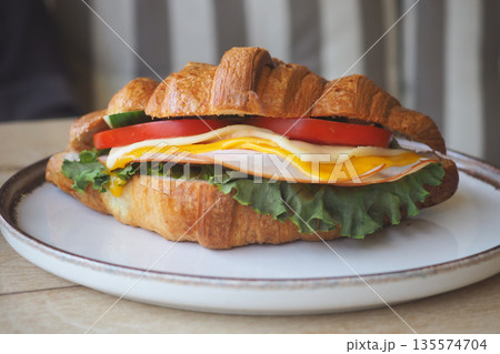 Delicious croissant sandwich with fresh ingredients served 135574704