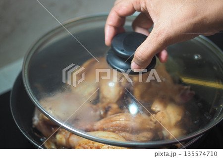 Cooking chicken in a pot on a stove in the kitchen Cooking chicken in a pot on a stove in the kitchen 135574710