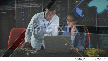 Collaborating lab technicians adjusting circuit boards at tech lab desk, with world map display Collaborating lab technicians adjusting circuit boards at tech lab desk, with world map display 135575433