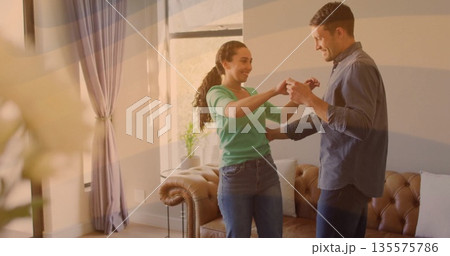 Dancing couple twirling in home living room, with brown leather sofa and potted plant Dancing couple twirling in home living room, with brown leather sofa and potted plant 135575786