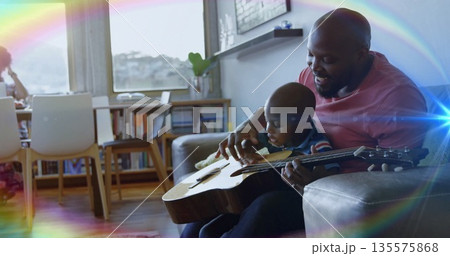 Guiding father and son learning guitar in modern home living area, with acoustic guitar, copy space 135575868