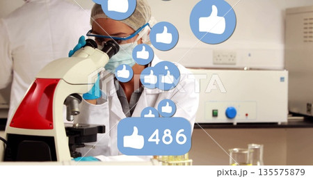 Observing scientist wearing coat examining microscope in lab, liquid test tubes and thumbs-up icons 135575879