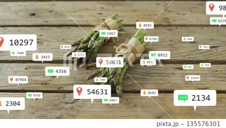 Displaying asparagus bundles sitting on wooden tabletop, with floating digital notification icons 135576301