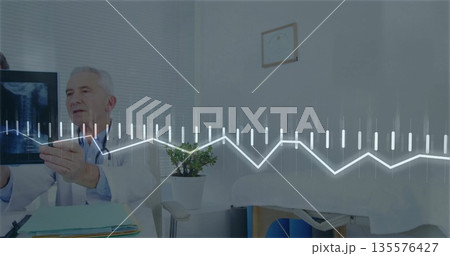 Senior doctor in white coat reviewing x-ray film in exam room, with stethoscope and graph overlay Senior doctor in white coat reviewing x-ray film in exam room, with stethoscope and graph overlay 135576427