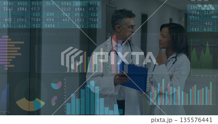 Reviewing data charts doctors in lab coats standing in hospital corridor, blue clipboard 135576441