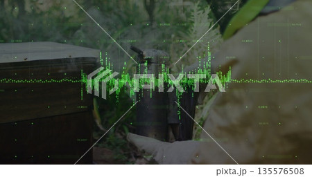 Beekeeper in yellow protective suit and gloves tending hive box using smoker at apiary, copy space 135576508