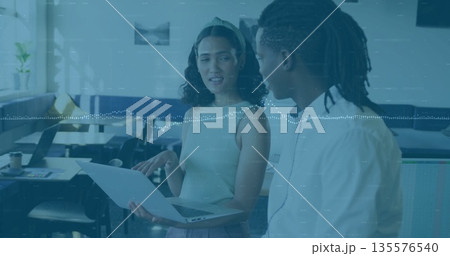 Pointing woman and listening man discussing project in modern office, with laptop and potted plant 135576540