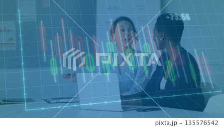 Two women in business attire reviewing candlestick chart at conference table with laptop and charts Two women in business attire reviewing candlestick chart at conference table with laptop and charts 135576542