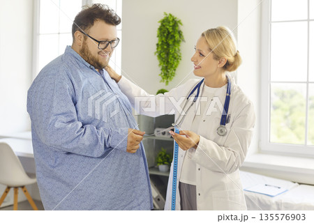 Friendly doctor discussing weight loss plan with obese male patient in clinic Friendly doctor discussing weight loss plan with obese male patient in clinic 135576903