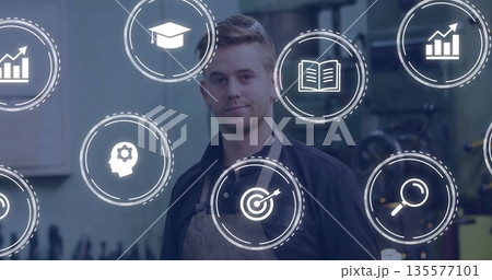 Male technician analyzing education data wearing apron in workshop, with floating analytics icons Male technician analyzing education data wearing apron in workshop, with floating analytics icons 135577101