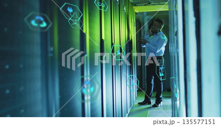 Inspecting technician making phone call in data center aisle, with server racks, icons, copy space 135577151