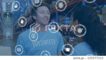 Reviewing male volunteer scanning boxes in warehouse aisle, with digital overlay icons, copy space Reviewing male volunteer scanning boxes in warehouse aisle, with digital overlay icons, copy space 135577315