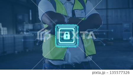 Standing worker wearing safety vest with crossed arms at metal racks, stacked pallets, digital lock Standing worker wearing safety vest with crossed arms at metal racks, stacked pallets, digital lock 135577326