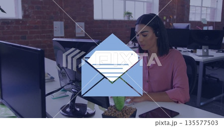 Support agent wearing pink blouse typing in office, with monitor, headset, papers, copy space Support agent wearing pink blouse typing in office, with monitor, headset, papers, copy space 135577503