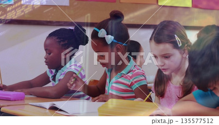 Elementary school children writing in classroom at wooden desks, using notebooks pencils cases 135577512