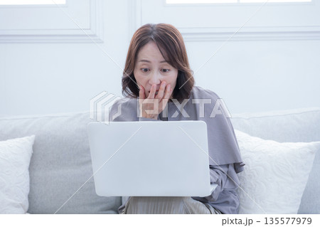パソコンを使い、これは詐欺？などビックリするシニア女性 135577979
