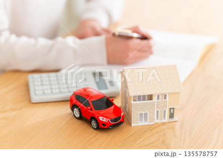 家計簿をつけるミドル女性の手元と家と車 135578757