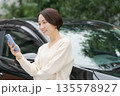 車の前でスマホを操作する女性 135578927