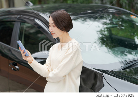 車の前でスマホを操作する女性 135578929