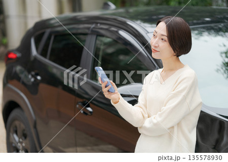 車の前でスマホを操作する女性 135578930