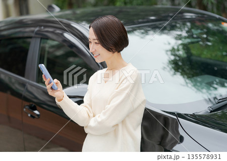 車の前でスマホを操作する女性 車の前でスマホを操作する女性 135578931