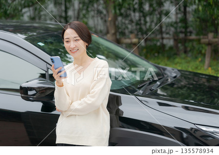 車の前でスマホを操作する女性 135578934
