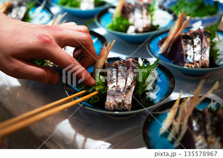 藁焼き鰹のタタキを盛り付ける 135578967