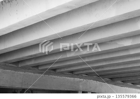 Underneath a concrete bridge, parallel beams form a bold industrial pattern 135579366