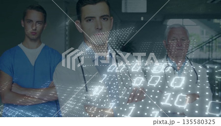 Standing medical team crossing arms in hospital corridor, with stethoscopes and binary data overlay Standing medical team crossing arms in hospital corridor, with stethoscopes and binary data overlay 135580325