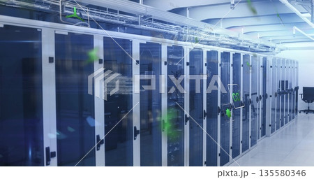Displaying server cabinets with blue LEDs and cable trays in data center corridor, with black chair 135580346