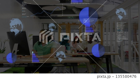 Collaborating team reviewing code at table in open-plan office, with laptops, holographic displays 135580476