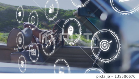 Driving Indian woman in striped top leaning out convertible window on road, with floating icons 135580670