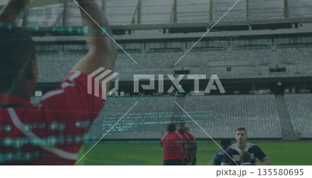 Group of rugby players practicing on grass at empty stadium, holding ball with code overlay 135580695