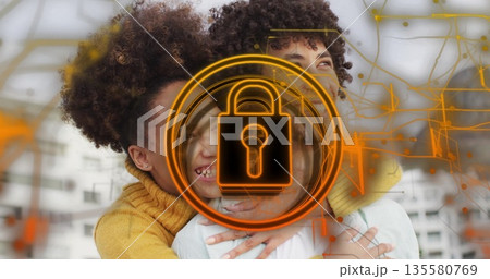 Embracing couple wearing white shirt and yellow sweater in loft, with orange padlock and circuits 135580769