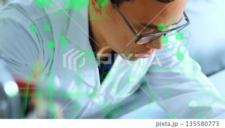 Analyzing scientist wearing lab coat and glasses leaning over lab bench, with molecular overlay Analyzing scientist wearing lab coat and glasses leaning over lab bench, with molecular overlay 135580773