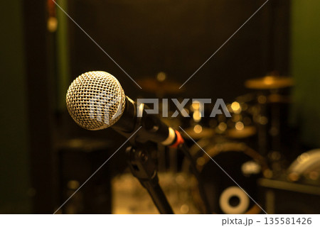 Microphone on Stand with Drum Set in Background at Music Studio 135581426